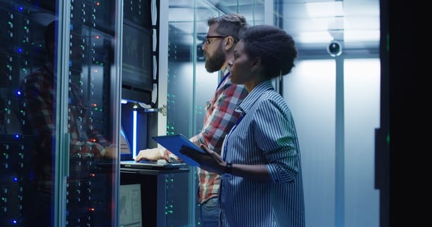 Two people standing in front of a server.