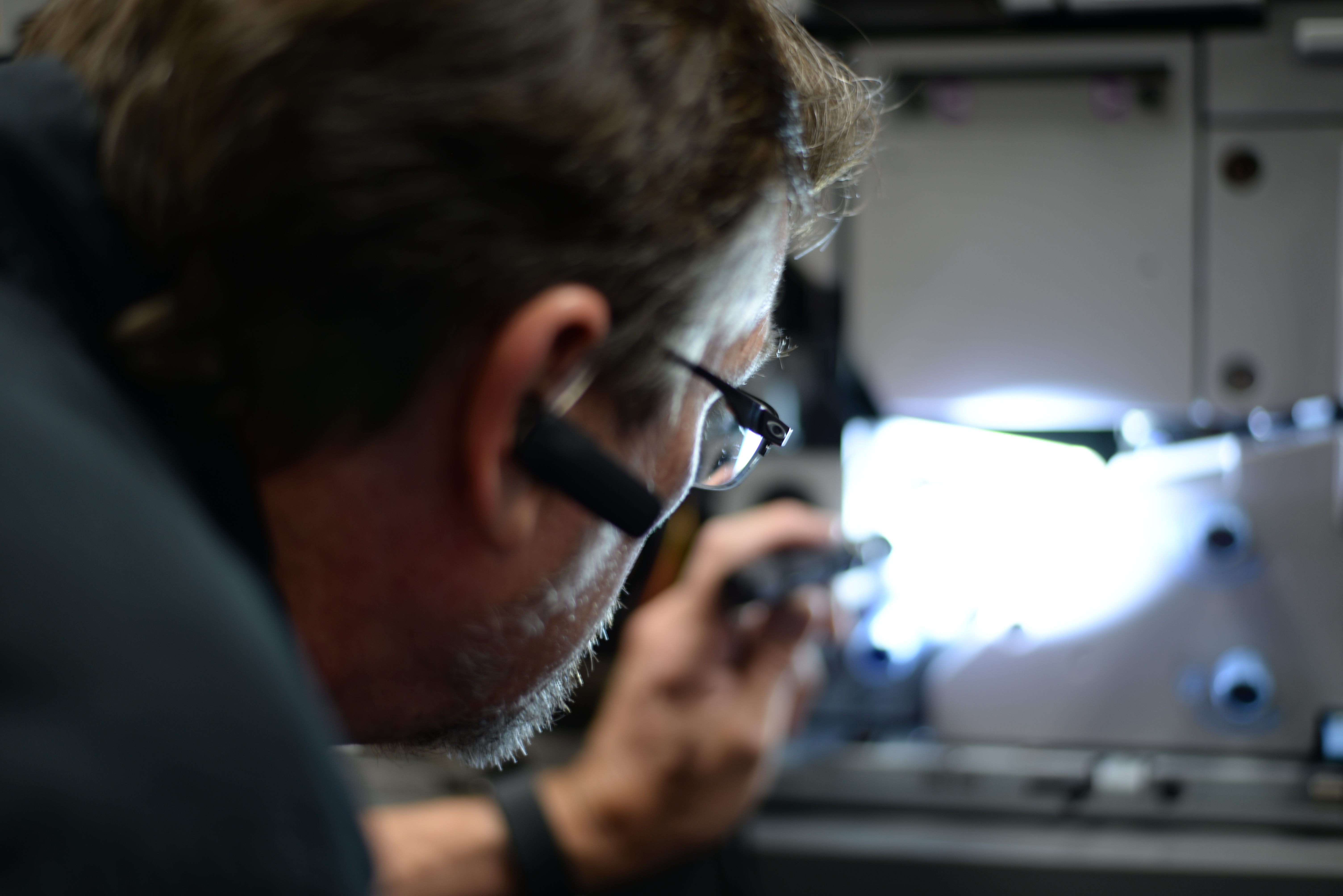 Photo of technician holding a flashlight, looking into a printer.